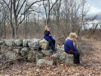 Harvey and Zion resting on a stone wall made of big stones